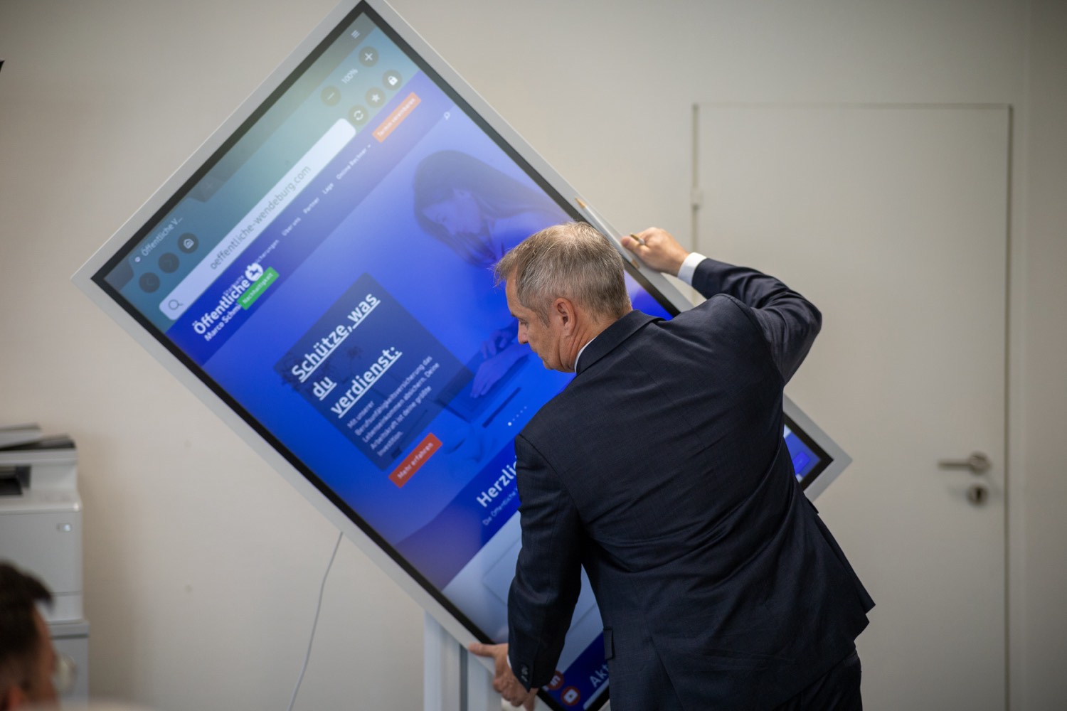 Marco Schmidt richtet einen digitalen Bildschirm in der Geschäftsstelle ein