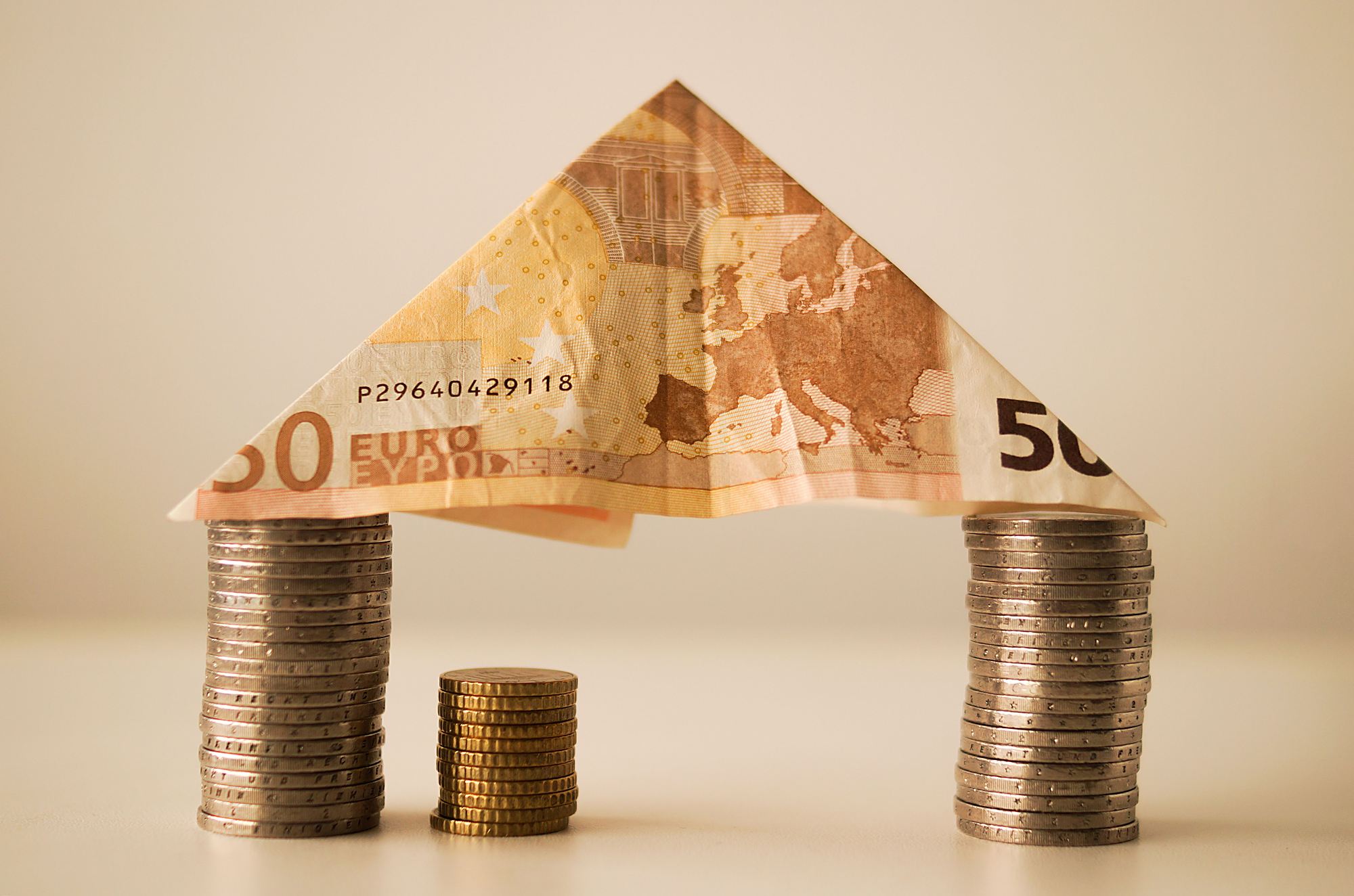Aus Münzstapeln und einem 50-Euro-Schein gebautes Haus als Symbol für Altersvorsorge